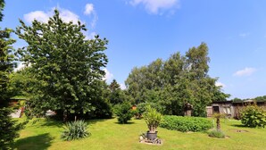 A well-maintained garden with various plants and a lawn. - Ferienwohnung in Brusow an der Ostseekueste (Kroepelin)