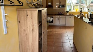 Eine Küche mit Holzausstattung, einer Trockenanlage für Fleisch und einem Fenster mit Vorhängen.