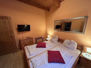 A bedroom with two beds, a TV, a mirror, a dresser, and a nightstand with a lamp. - Gemuetlicher Bungalow am Meer in Pepelow (Am Salzhaff)