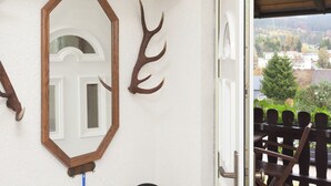 Quarto com porta branca, espelho com moldura de madeira e decorações de chifres na parede.