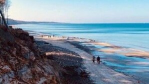 En kustvy med en strand, en klippig terräng och fri sikt ut över havet.
