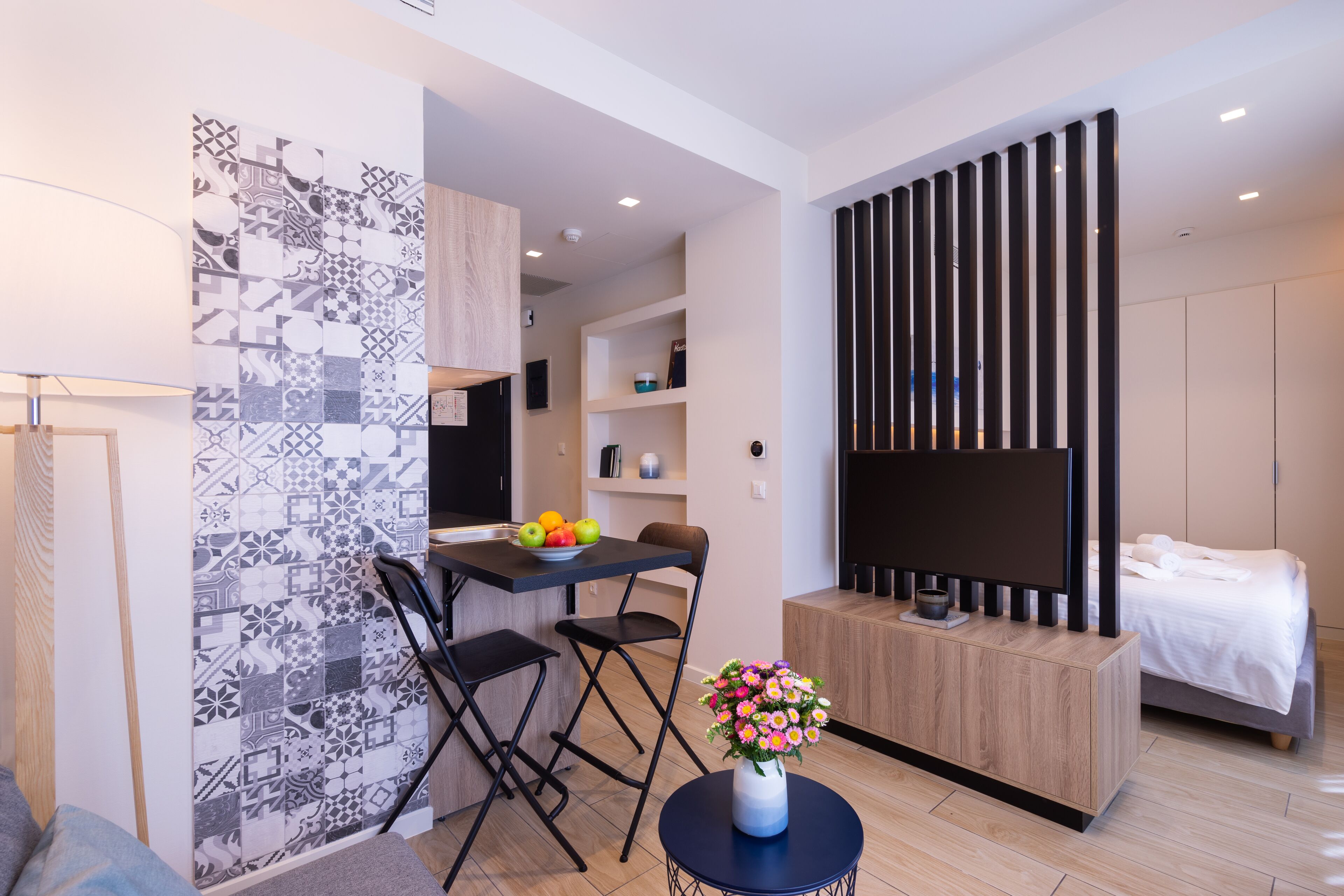 A modern, compact living space with a kitchenette, a dining area, and a bedroom.