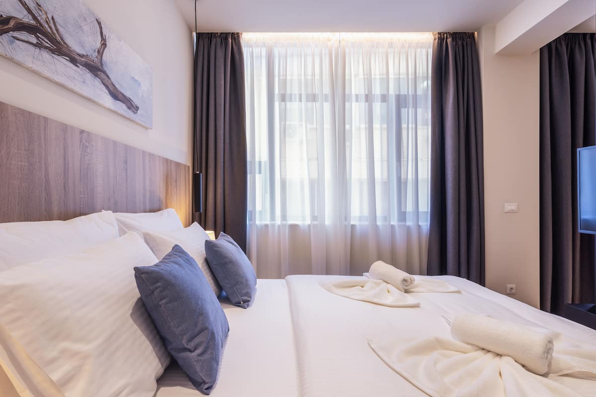 Een hotelkamer met een groot bed, een flatscreen televisie en een raam met dunne gordijnen.