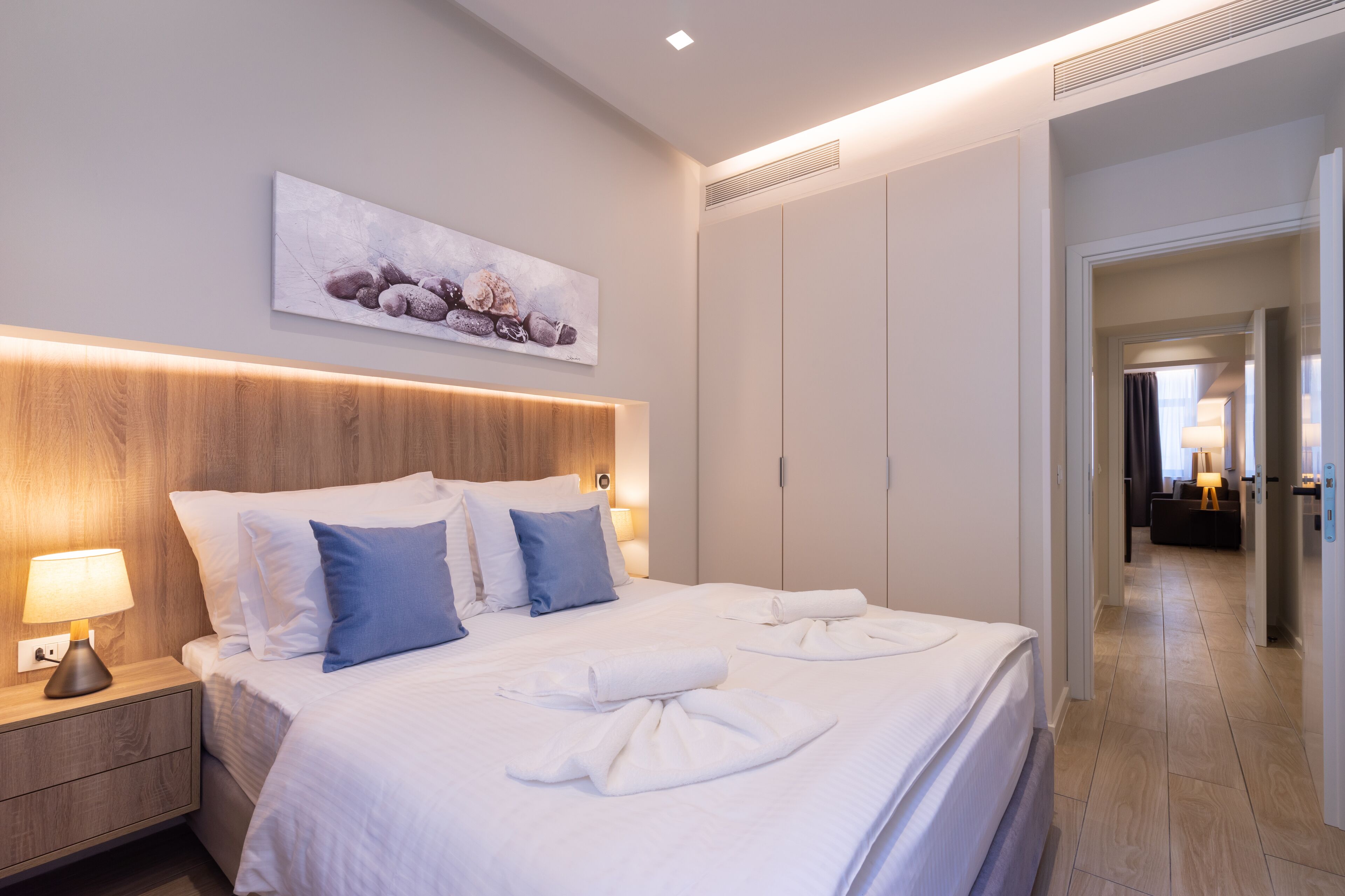 Een moderne hotelkamer met een groot bed, nachtkastjes, een hoofdbord en een schilderij aan de muur.