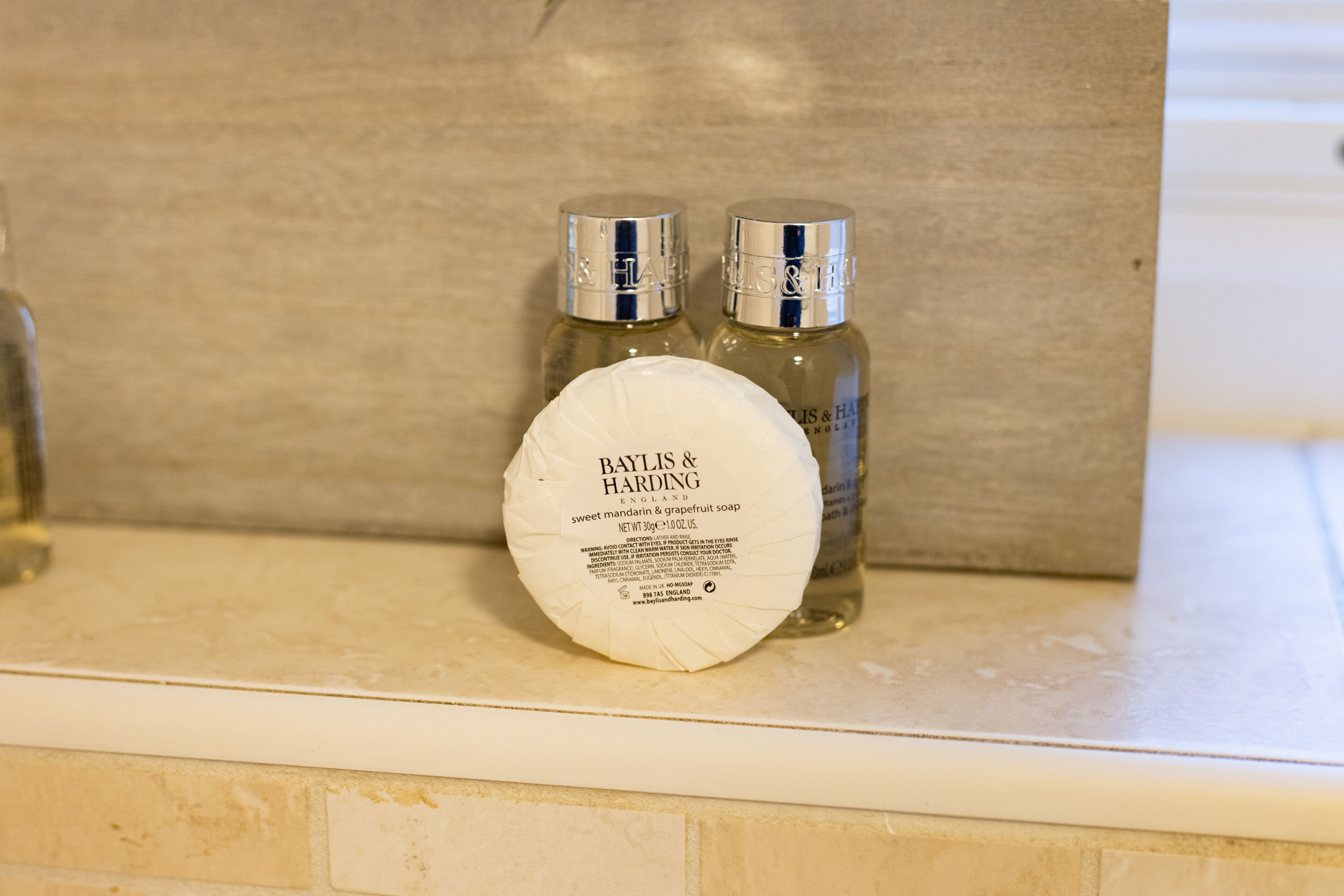 Een Baylis & Harding zeepstaafje en twee flessen handcrème op een badkamermeubel.
