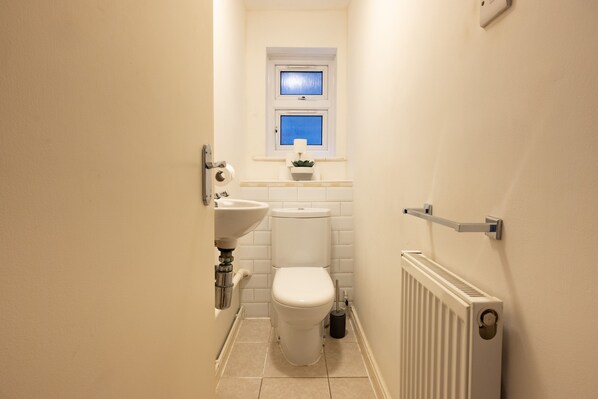 A small, clean bathroom with a toilet, sink, and window.