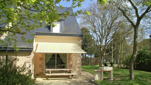 Een huis met een terras, een picknicktafel en een kleine tuin.