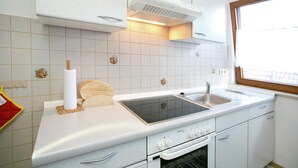 A modern kitchen with white cabinets, a double sink, a built-in oven, and a window providing natural light. - Spacious Apartment near Lake Constance with Covered Balcony (Bermatingen)