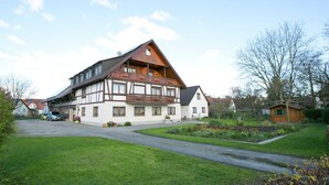 A large, two-story house with a sloped roof and wooden balcony railings. - Spacious Apartment near Lake Constance with Covered Balcony (Bermatingen)