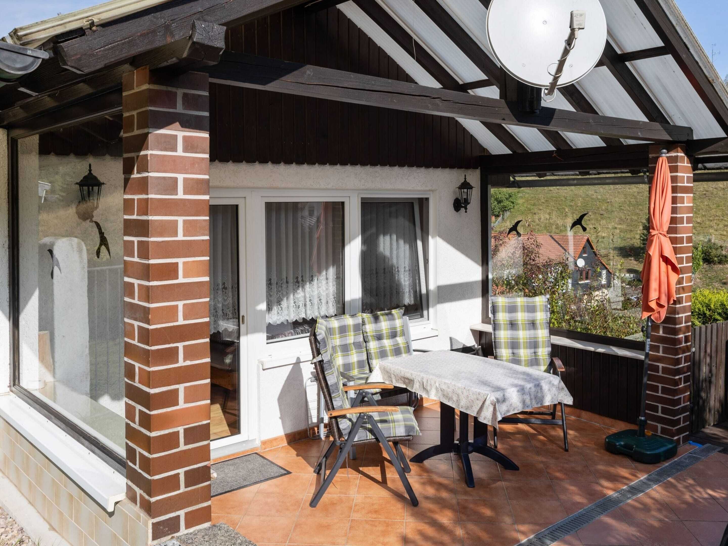 A cozy patio with a table and chairs, a brick wall, and a view of the countryside.