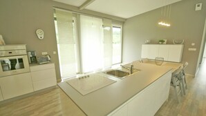 A modern kitchen with a large island, a built-in oven, and a coffee maker. - Family Escape With Garden (Saint-Quirin)
