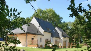 Une maison à deux étages, dotée d’un toit en pente, d’un porche couvert et d’une cour clôturée.