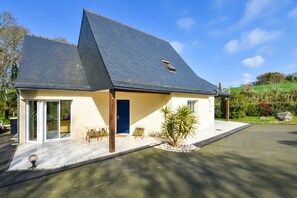 A modern house with a sloped roof, a front door, and a patio area with outdoor furniture. - Coastal Retreat in Plurien (Plurien)