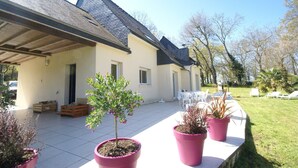 Un bâtiment doté d’un patio couvert, de plantes en pot et de mobilier d’extérieur.
