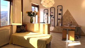 A room with a bed, a desk, a radiator, a window with a view, and a decorative hanging light. - Modern Poolside Home in Pescia (Pescia)