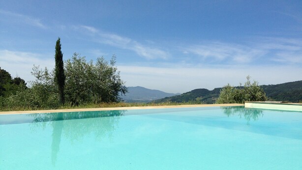 A clear blue swimming pool with a view of distant hills and trees. - Modern Poolside Home in Pescia (Pescia)