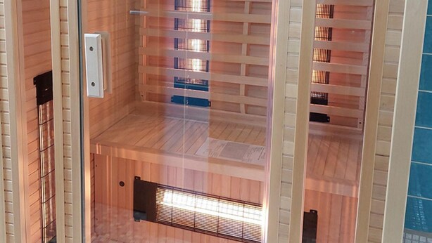 A sauna with a glass door, wooden interior, and a control panel on the wall. - Holiday Home Near Monschau With a Sauna (Schleiden)