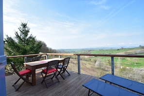 A wooden deck with a table and chairs, overlooking a green landscape. - Mansion in Cuzy With Pool and Scenic Views (Cuzy)