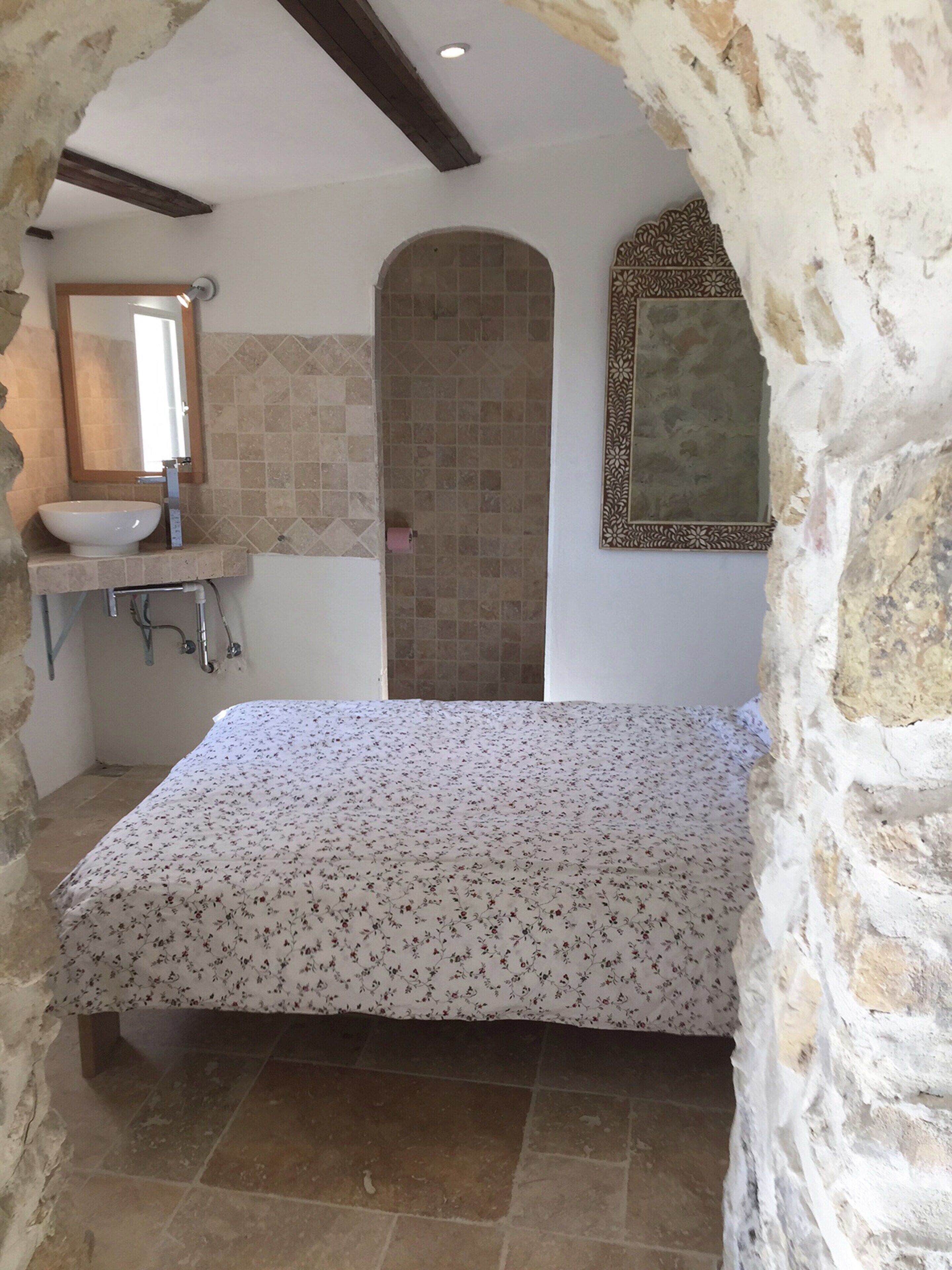 Una habitación con cama, lavamanos y espejo.
