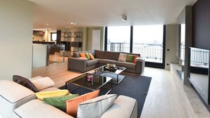 A modern living room with a sofa set, a coffee table, and a dining area in the background. - Luxurious Apartment in Nieuwpoort with Hot Tub (Nieuwpoort)