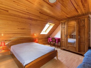 A wooden-paneled room with a bed, a table with chairs, and a wardrobe. - Charming Stay in Pont-croix (Pont-Croix)