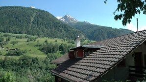 A traditional house with a tiled roof, surrounded by lush greenery and mountains in the background. - Charming Chalet Near Trails (Mörel-Filet)