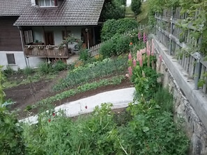 A residential property with a garden, a wooden fence, and a house with a tiled roof. - Charming Chalet Near Trails (Mörel-Filet)