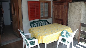A dining area with a table covered in a yellow floral tablecloth, surrounded by white chairs with green cushions. - Charming Chalet Near Trails (Mörel-Filet)