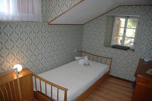 A small, neatly arranged bedroom with a single bed, a window with a view, and a nightstand with a lamp. - Charming Chalet Near Trails (Mörel-Filet)