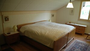 A bedroom with a wooden bed, a nightstand, a desk, and a window. - Charming Chalet Near Trails (Mörel-Filet)