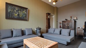 Un salon avec deux canapés gris, une table basse en bois, une horloge et un tableau accroché au mur.