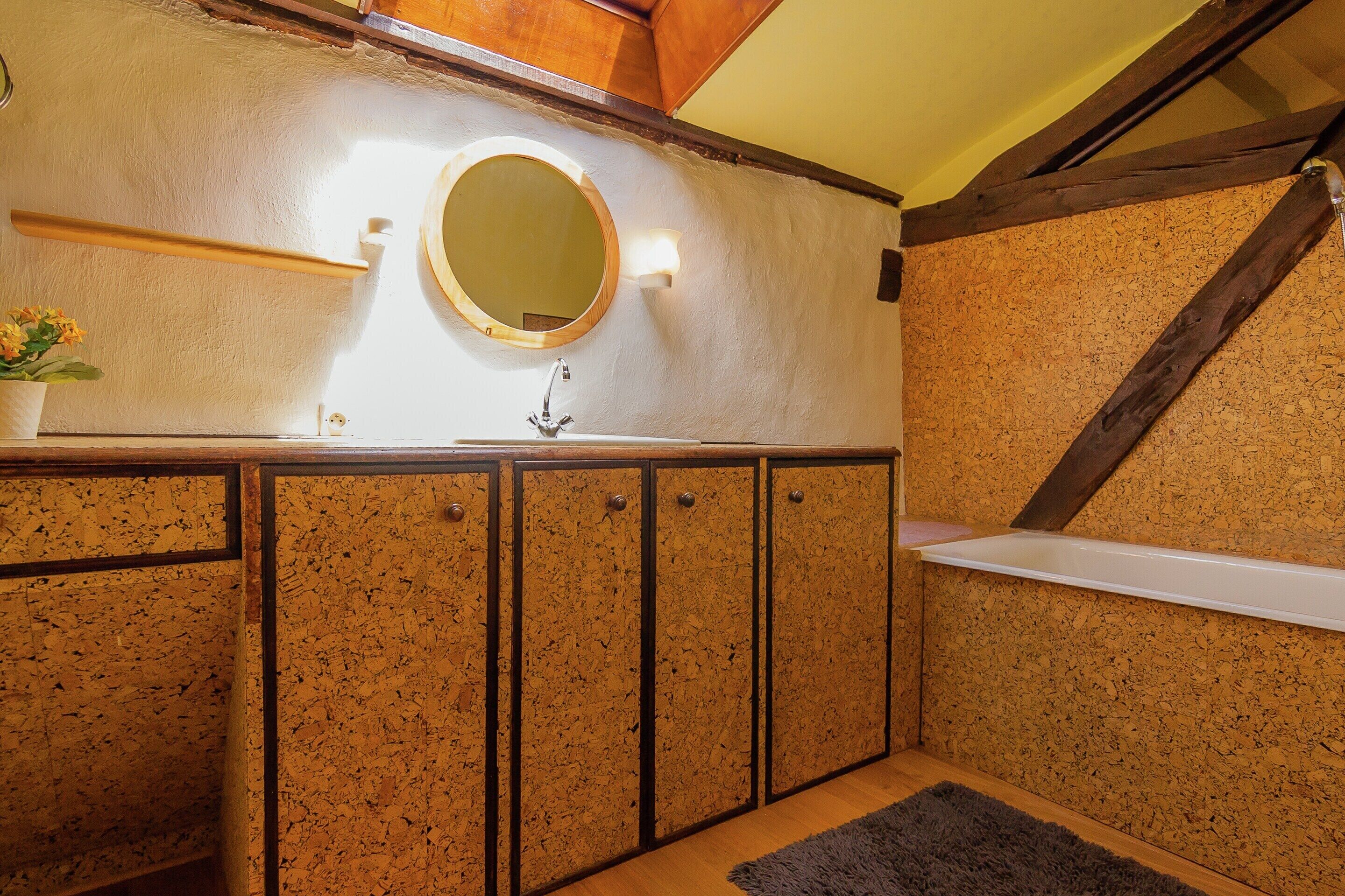 A bathroom with a wooden vanity, a round mirror, and a built-in shelf.