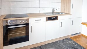 A modern kitchen with white cabinets, a stainless steel range, a dishwasher, and a wooden countertop. - Apartment in Tropolach Near Nassfeld (Hermagor-Pressegger See)
