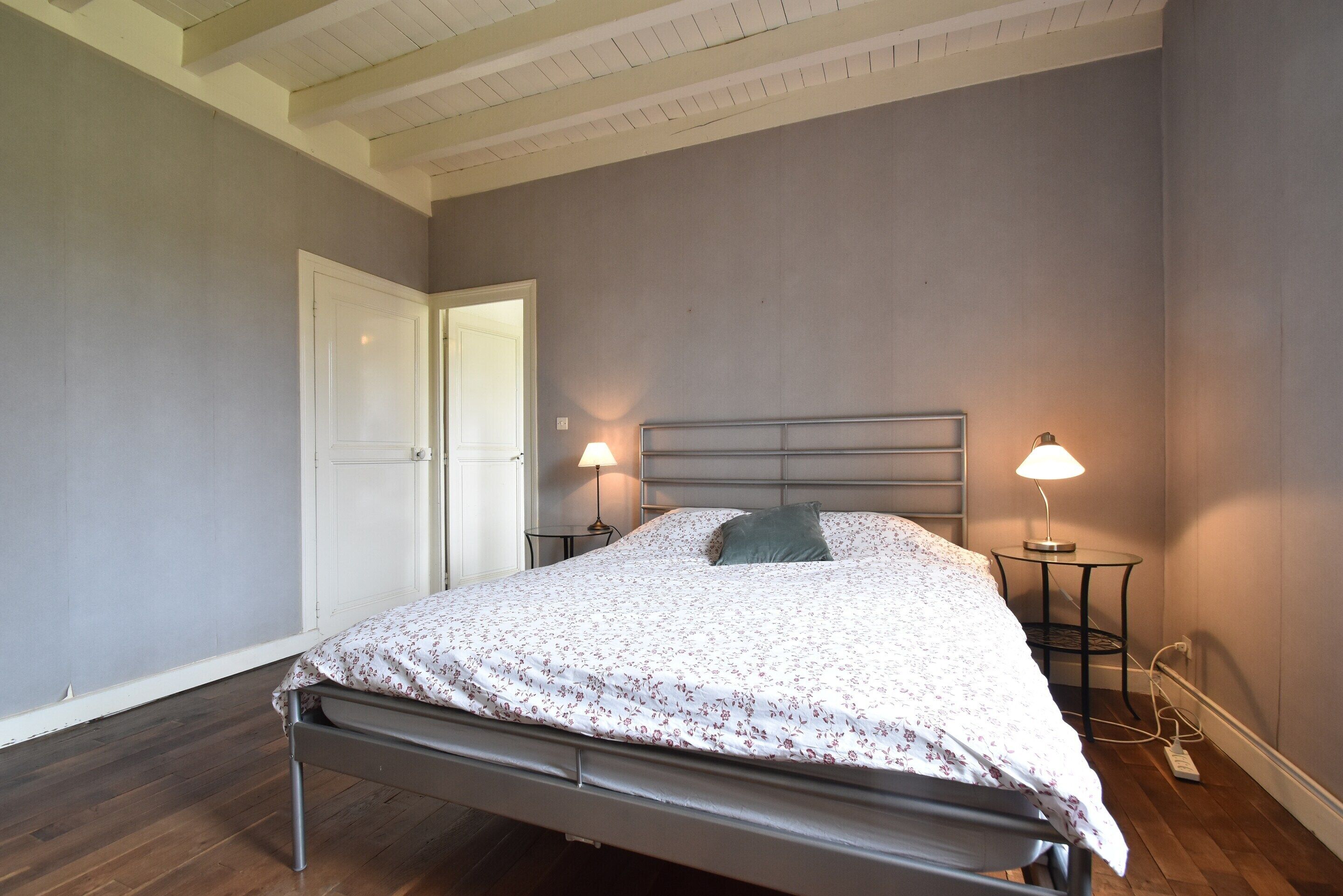 Une chambre à coucher avec un lit, deux lampes de chevet, une porte et une prise de courant.