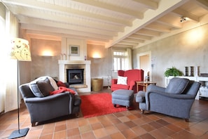 A living room with a fireplace, two sofas, a red rug, and a tiled floor. - Mansion in Charrin by Loire With Pool (Charrin)