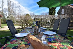 An outdoor dining table with chairs, a loaf of bread, a bottle, and a green umbrella. - Mansion in Charrin by Loire With Pool (Charrin)