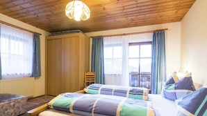 Ein Schlafzimmer mit zwei Betten, Holzboden und einem Fenster mit Vorhängen.