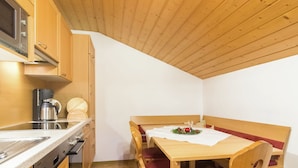 Eine kompakte Küche mit Holzschränken, einer Kaffeemaschine und einem Essbereich mit Tisch und Stühlen.