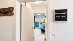 A hallway leading to a balcony with a view, a sign reading "APARTMENT ST. MICHAEL", and a rustic wooden decoration on the wall.
