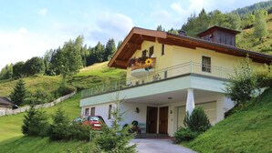 A two-story house with a balcony, surrounded by greenery and hills. - Sunlit Apartment near Ski Area in Hüttschlag (Huettschlag)