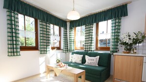 A cozy room with a green sofa, a wooden table, and a white rug. - Sunlit Apartment near Ski Area in Hüttschlag (Huettschlag)