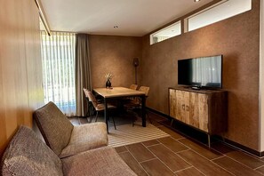 Una sala de estar moderna con un sofá, una mesa de comedor, sillas, un televisor y un armario.