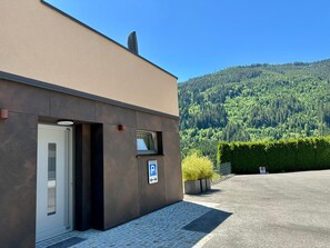 En byggnad med en parkeringsskylt, en dörr och utsikt över en skogbeklädd kulle.