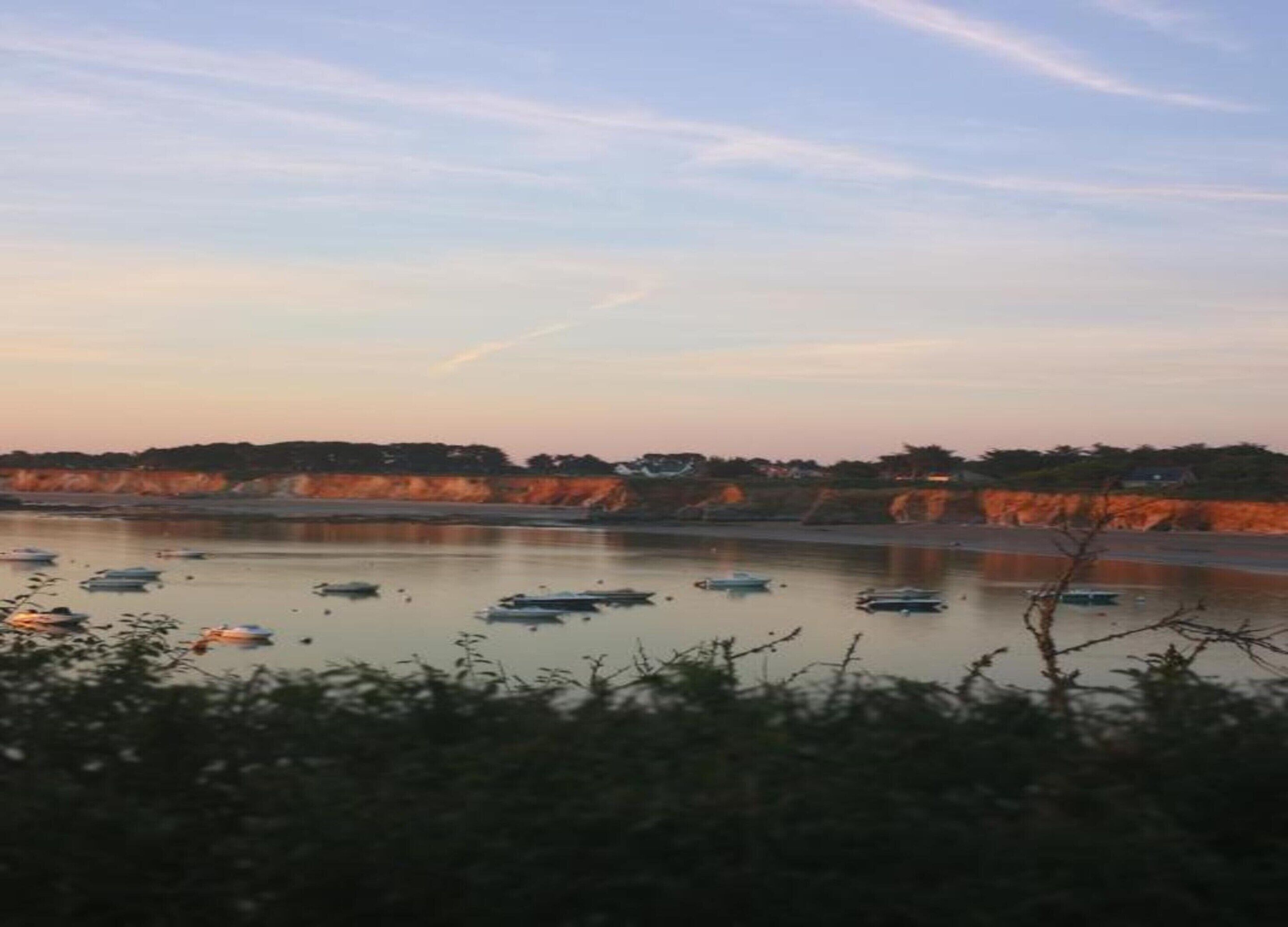 Un río con barcos, una orilla distante y un cielo despejado.
