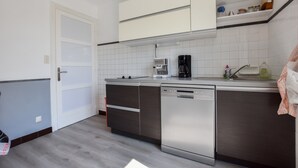 Una cuina moderna amb rentaplats, cafetera i salabost de rajola blanca.