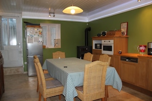 A dining area with a table set for four, surrounded by wicker chairs, a refrigerator, a microwave, and a sink in the background. - Villa With Spa & Pool (Channay)