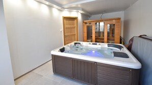 Uma banheira de hidromassagem num canto do quarto, com uma porta de madeira e um armário com portas de vidro.