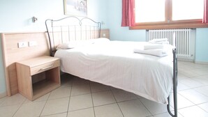 A bedroom with a bed, bedside table, and a window with curtains. - Apartment 2 in Baita Near the Ski Lifts (Livigno)