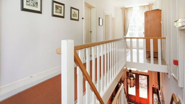 A staircase with white railings and a wooden handrail, leading to a lower level. There are framed pictures on the wall above the staircase. - Holiday Home With Sauna (Swolgen)
