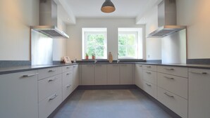 Une cuisine moderne avec des meubles blancs, un plan de travail noir et une grande fenêtre qui laisse entrer la lumière naturelle.